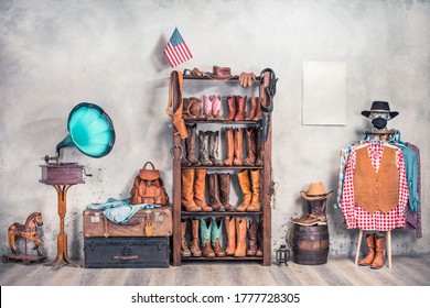 Wild West Still Life. Retro Leather Boots, Hats, Clothes, Holsters, USA Flag, Old Gramophone, Barrel And Poster Blank On A Wall. Cowboy Store Interior Conceptual Design. Vintage Style Filtered Photo