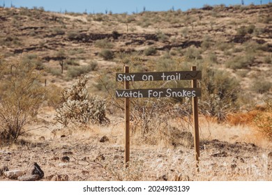 The Wild West. Western old city in Phoenix, Arizona, USA. Gold rush city. Old Arizona. A ‘Stay on Trail Watch for snakes’ sign in the desert. Wooden sign with an inscription. 
