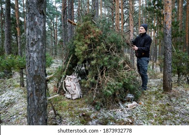 Wilderness Survival Camp - Man Building Tree Branch Hut In Forest In Winter