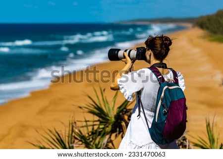 wildlife photographer takes photo of wild animals at rural australian beach in queensland; professional camera and large, long lense used to capture native fauna	