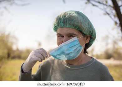 I Will Protect Myself And Others. Senior Woman At Nature Wearing Face Mask And Medical Cap. Close Up.