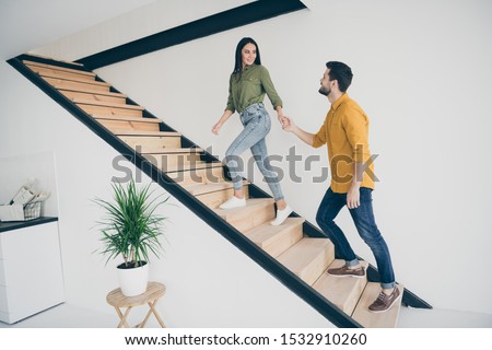 I will show you our bedroom! Full length profile photo of handsome guy and his pretty lady going up stairs in new modern flat indoors wear casual clothes