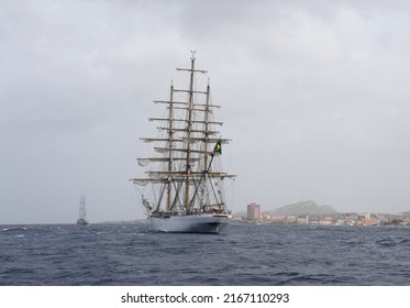 Willemstad, Curacao - June 12, 2022: Cisne Branco cruising along the coastline with the skyline in the background, seen from the ocean; sail away during the Velas Latinoamérica Curaçao 2022 festival 