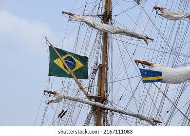 Willemstad, Curacao - June 12, 2022: Brazilian flag closeup on the Cisne Branco with a sailor climbing in the rigging during sail away at Velas Latinoamérica Curaçao 2022 festival in Curacao 