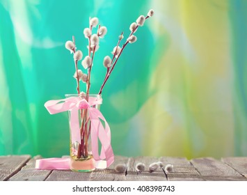 Willow branches with a pink tape in a transparent vase. A bouquet for a Palm Sunday, a flavovirent background, a wooden white table, soft focus