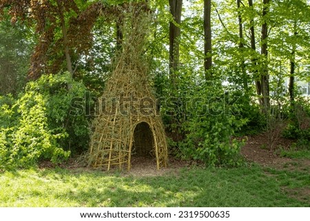 willow teepee in the garden with grass and trees in the background