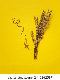 Willow twigs and Christian cross on a string, yellow background