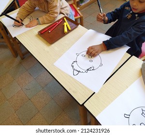 Wilsele, Flemish Brabant, Belgium - February 15, 2022: 2 toddlers age 3 one girl multi ethnic in a real situation kindergarten classroom learn drawing circles by exercising drawing a human head
