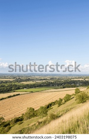 Wiltshire, England farm countryside, blue sky over a patchwork of fields, blue sky with puffy clouds.