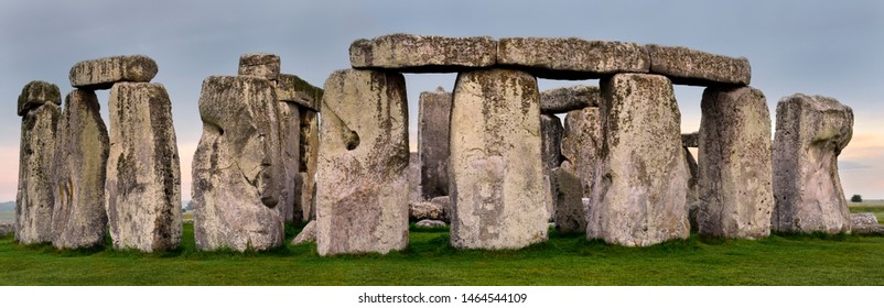Wiltshire, England - June 10, 2019: Wide Panorama of Stonehenge prehistoric stone circle ruins amongst farm fields in Wiltshire England at sunrise