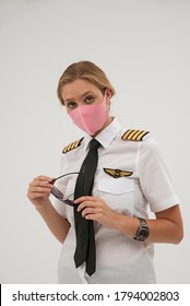 Wiltshire, England, UK. August 2020.  Airline Pilot Wearing A Face Mask And Holding Sun Glasses During The Covid-19 Lockdown. 