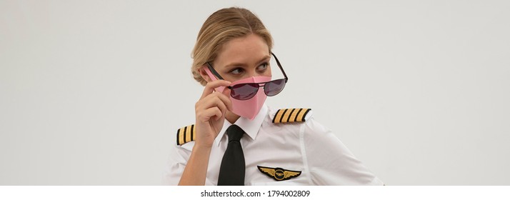 Wiltshire, England, UK. August 2020.  Airline Pilot Wearing A Face Mask And Holding Sun Glasses During The Covid-19 Lockdown. 