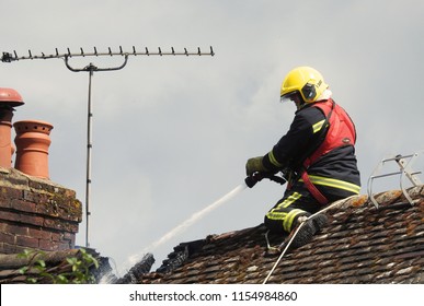 Wiltshire, UK. August 13 2018. A Firefighter On A Roof Tackling A Residential House Fire           