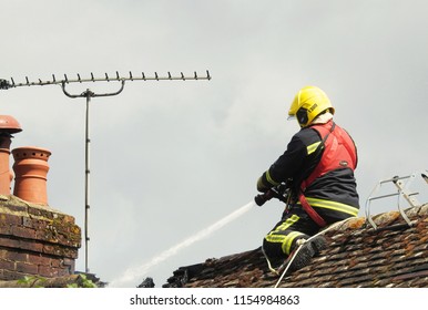 Wiltshire, UK. August 13 2018. A Firefighter On A Roof Tackling A Residential House Fire           