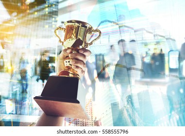Win concept,Man holding up a gold trophy cup is winner in a competition with cityscape background. - Shutterstock ID 558555796