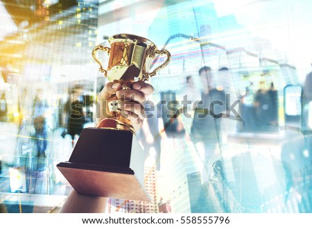 Win concept,Man holding up a gold trophy cup is winner in a competition with cityscape background.