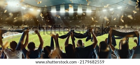 Win, victory, celebration. Back view of football, soccer fans cheering their team with colorful scarfs at crowded stadium at evening time. Concept of sport, cup, world, team, event, competition