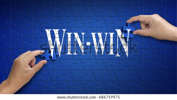 win win word on Jigsaw puzzle - business\
concept. Man hand holding a blue puzzle to complete the word\
win-win divided over them concept of the solution to a problem,\
challenge, plan and\
strategy.