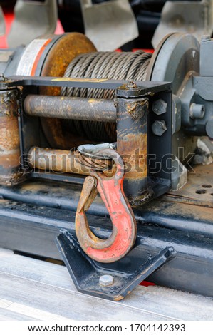 Winch on a towtruck with hook and metal cable.