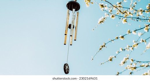 Wind chime with zen symbolism hanging on tree in blossom with copy space