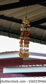 A wind chimes made of shells hanging from the roof of a Thai home