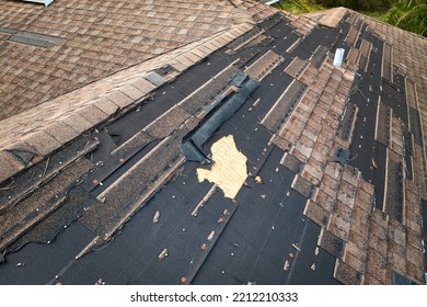 Wind Damaged House Roof With Missing Asphalt Shingles After Hurricane Ian In Florida. Repair Of Home Rooftop Concept