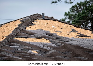 Wind Damaged House Roof With Missing Asphalt Shingles After Hurricane Ian In Florida. Repair Of Home Rooftop Concept