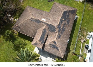 Wind Damaged House Roof With Missing Asphalt Shingles After Hurricane Ian In Florida. Repair Of Home Rooftop Concept