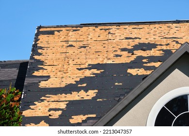 Wind Damaged House Roof With Missing Asphalt Shingles After Hurricane Ian In Florida. Repair Of Home Rooftop Concept