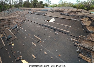 Wind Damaged House Roof With Missing Asphalt Shingles After Hurricane Ian In Florida. Repair Of Home Rooftop Concept