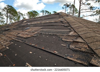 Wind Damaged House Roof With Missing Asphalt Shingles After Hurricane Ian In Florida. Repair Of Home Rooftop Concept