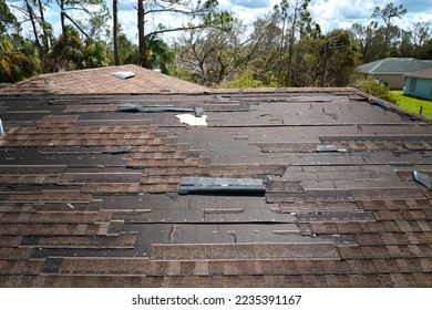 Wind damaged house roof with missing asphalt shingles after hurricane Ian in Florida. Repair of home rooftop concept - Shutterstock ID 2235391167