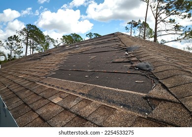 Wind damaged house roof with missing asphalt shingles after hurricane Ian in Florida. Repair of home rooftop concept - Shutterstock ID 2254533275