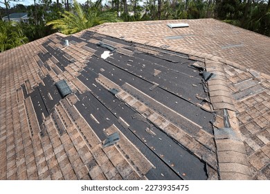 Wind damaged house roof with missing asphalt shingles after hurricane Ian in Florida. Repair of home rooftop concept