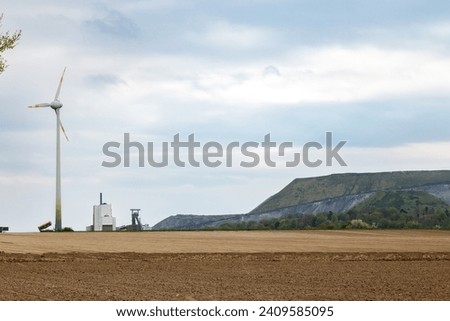 A wind generator in a field next to a dump of empty mine rocks