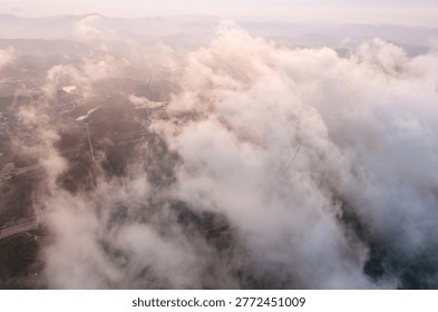 Wind generators amidst clouds in mountainous landscape, Vietnam.