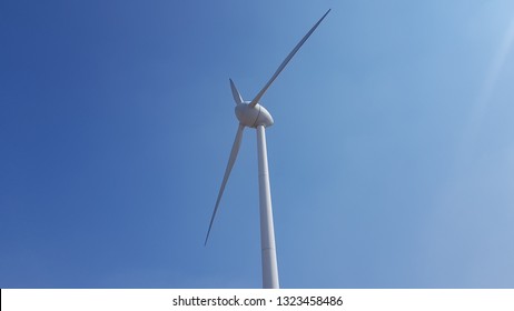 Wind Generators, Road To Energy Transition On A Hill And A Background Of Blue Sky.