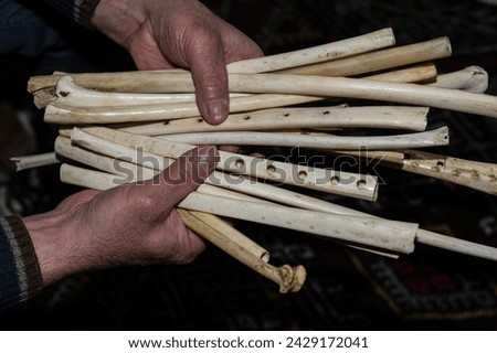 A wind instrument made of eagle wing bones in the hands of a man. Its Turkish name is 