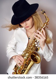 Wind is messing up hair of the beautiful  girl with saxophone