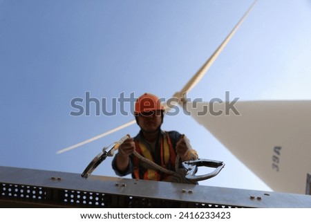 Wind mill worker with safety harness and ppe working under wind turbine 
