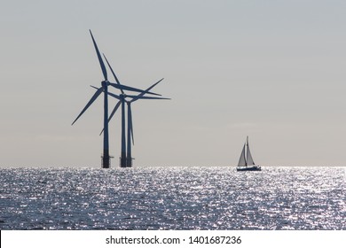 Wind Power. Environmentally Friendly Sailing Yacht. Offshore Windfarm Turbines. Tranquil Scene Of Renewable Resource Power And Travel With Low Carbon Footprint Lifestyle. Ecology Landscape.