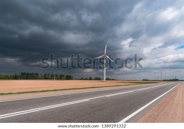 Wind power. Wind power plant. Wind farm Wind\
generators in a field near the highway. Production of alternative\
green renewable energy