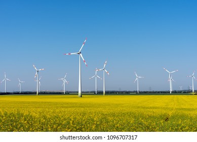 Wind power plants in a blooming rapeseed field seen in rural Germany