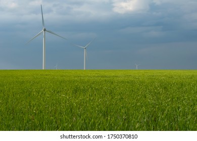 Wind power turbines among green meadow with blue sky in the spring morning. Copy space for text. Green energy concept. - Powered by Shutterstock