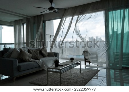 The wind rustles the curtain of the panoramic window with a cityscape.