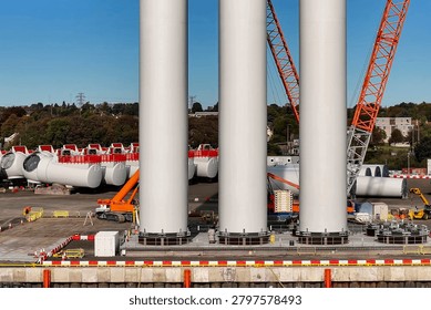 Wind tower sections aligned on dock with crane and assembly equipment
