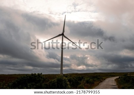 Wind turbine in a big open field. County Galway, Ireland. Production of clean electric energy. Dark dramatic sky. Nobody. Green renewable source of power.