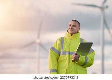 Wind turbine engineer. Male engineer maintains and controls wind turbine energy generation on the background of windmills. Concept of sustainable future. - Powered by Shutterstock