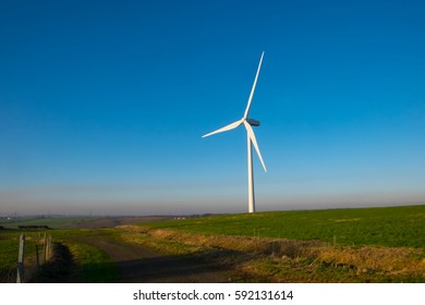 Wind Turbine In English Countryside Against Clear Blue Sky. Wind Power Is Part Of The Net Zero Emissions Target For The UK