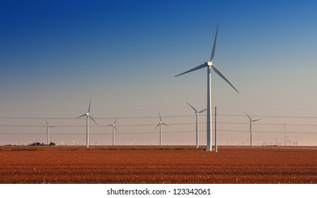 Wind Turbine Farm In Cotton Fields In West Texas.   High Voltage Power Lines Also Running Through Image